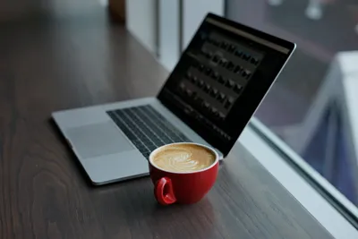 A modern laptop on a wooden tabletop near huge panoramic windows. Coffee  cup and writing utensils on the table. Autumn background. Remote work  concept 31765959 Stock Photo at Vecteezy