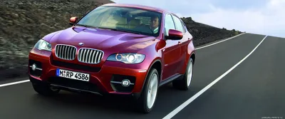 Обои на рабочий стол Мужчина едет за рулем бордового BMW X6 2019 по трассе  на фоне гор, обои для рабочего стола, скачать обои, обои бесплатно