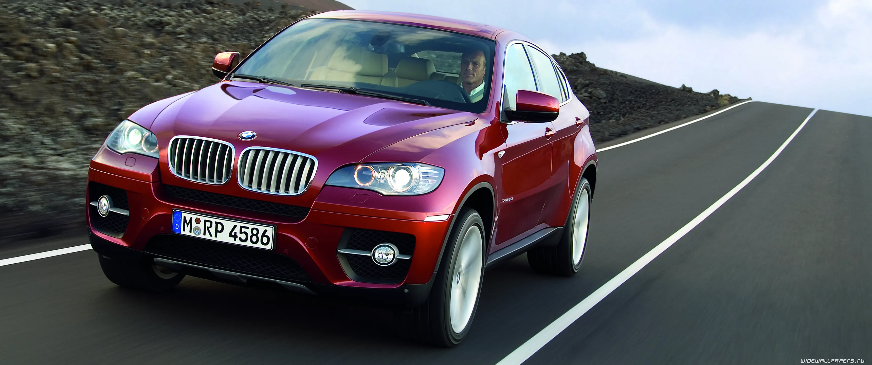 Обои на рабочий стол Мужчина едет за рулем бордового BMW X6 2019 по трассе на фоне гор, обои для рабочего стола, скачать обои, обои бесплатно Обои на рабочий стол Мужчина едет за рулем бордового BMW X6 2019 по трассе на фоне гор, обои для рабочего стола, скачать обои, обои бесплатно