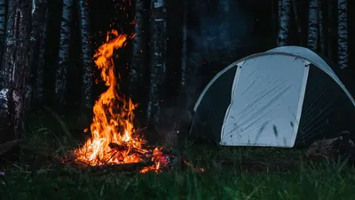 Сжигание дров ночью костер в туристическом лагере на природе в горах пламя  и искры огня на темном абстрактном фоне | Премиум Фото